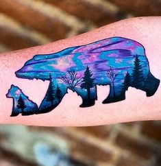 a bear and cub tattoo on the left arm, with trees in the foreground