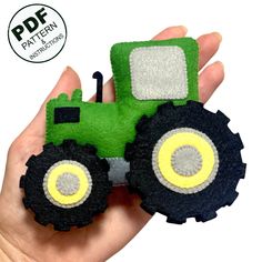 a hand holding a small green toy tractor