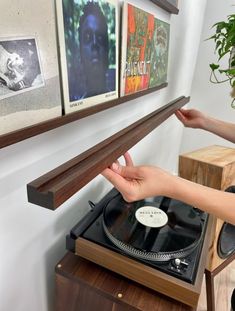 a person is holding a record player in front of a wall with pictures on it