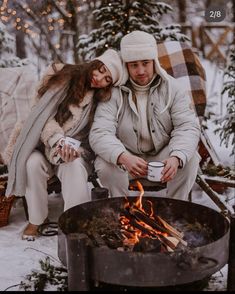 a man and woman sitting next to an open fire