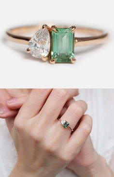 a woman's hand holding an emerald and diamond ring with two diamonds on it