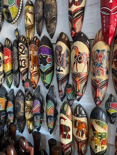 many different colored masks are hanging on the wall