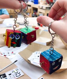 two people are holding small wooden blocks with faces on them and chains attached to them