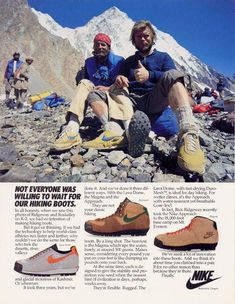 two men sitting on the rocks with their feet up and wearing hiking shoes, in front of a mountain