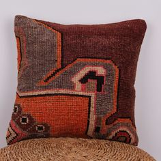 a brown and orange pillow sitting on top of a wooden chair next to a straw hat