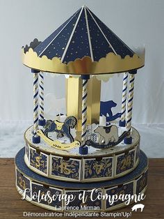 a carousel with blue and gold trimmings sits on a wooden table in front of a white wall