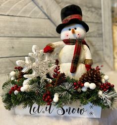 a snowman sitting on top of a box filled with pine cones