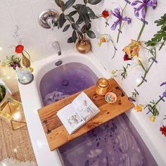 a bathtub filled with purple liquid next to flowers