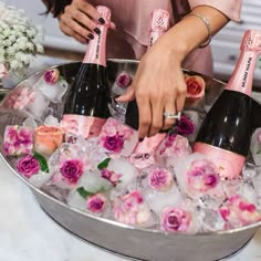 a woman is holding a bottle of champagne in an ice bucket with roses on it