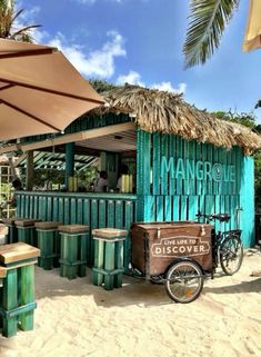 a bike parked next to a building on the beach with tables and chairs under umbrellas