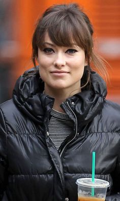 a woman in black jacket holding a drink