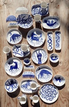 a table topped with lots of blue and white plates covered in animal designs next to a comb