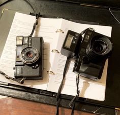 two cameras sitting on top of an open book