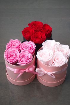 three pink and two red roses are in the shape of heart shaped boxes with ribbons