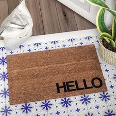 a door mat with the word hello written on it next to a potted plant