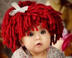 a baby wearing a red knitted hat with cherries on it's head