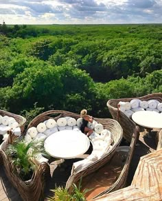 two wicker chairs with round tables on them in the middle of an open field