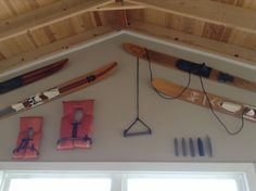 there are many different types of canoes hanging on the wall in this room, including kayaks and paddles