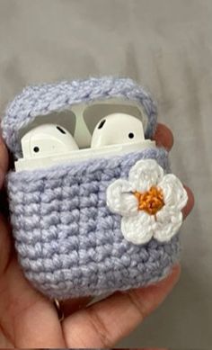 a crocheted case with two airpods in it and a flower on the inside