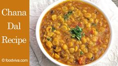 a bowl filled with beans and spinach on top of a white cloth next to a spoon