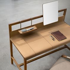 a wooden desk with a laptop, notebook and pen on it in an empty room