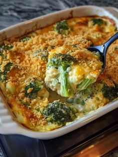 a casserole dish with broccoli and cheese being lifted from the oven