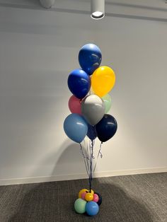 a bunch of balloons that are sitting on the ground in front of a white wall