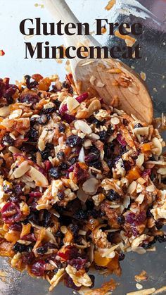 a bowl filled with granola, nuts and cranberries next to a wooden spoon