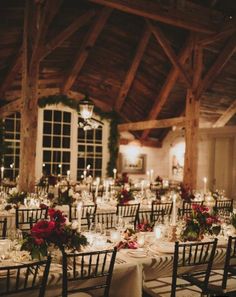 the tables are set with white linens and red flowers, candles and greenery