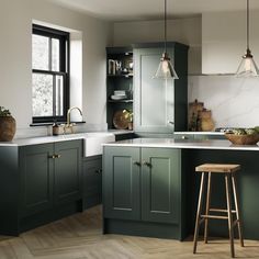 a kitchen with green cabinets and wooden stools in the center, along with white counter tops