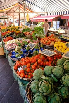 an open air market with lots of fresh fruits and vegetables in baskets on display for sale