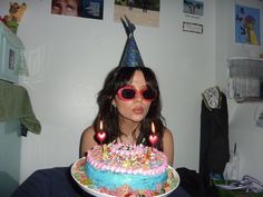 a woman wearing sunglasses and holding a birthday cake with lit candles in front of her