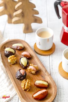 a wooden tray topped with lots of different types of food next to a cup of coffee