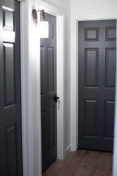 an empty hallway with two black doors and one white door