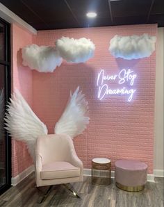 a pink room with white angel wings on the wall