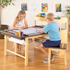 two children sitting at a wooden table playing with their art supplies in the living room