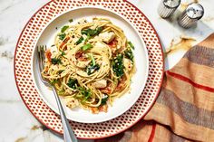 a white plate topped with pasta covered in sauce and spinach next to a fork