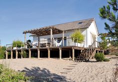 a house on the beach with a hammock hanging from it's roof