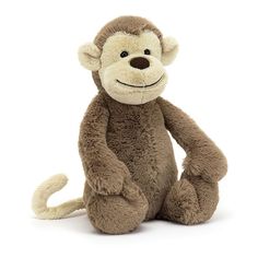 a stuffed monkey sitting on the ground with its legs crossed and eyes wide open, smiling