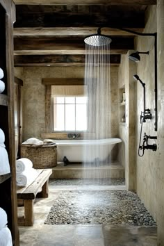 a bath room with a shower head next to a sink and a tub filled with white towels