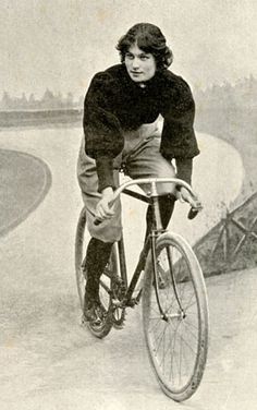 an old photo of a woman riding a bike