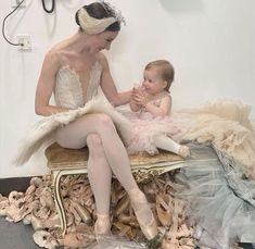 a woman sitting on top of a chair next to a baby in a ball gown