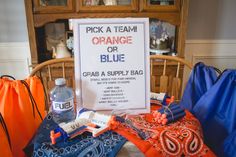 an orange and blue bag sitting on top of a table next to a sign that says pick a team orange or blue grab a supply bag