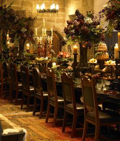 a dining room table is set with candles and flowers in tall vases on the tables