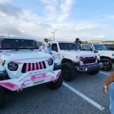 several jeeps are parked in a parking lot with people standing around them and taking pictures