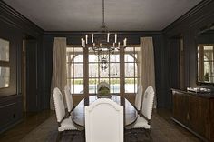 a dining room table with white chairs and a chandelier