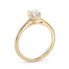 a yellow gold engagement ring with a single diamond in the center, on a white background