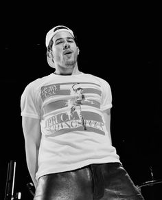 a man standing on top of a stage wearing leather pants and a t - shirt