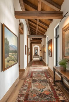 a long hallway with wooden beams and paintings on the walls, along with a bench