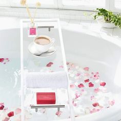 a white bath tub filled with lots of water next to a cup and saucer